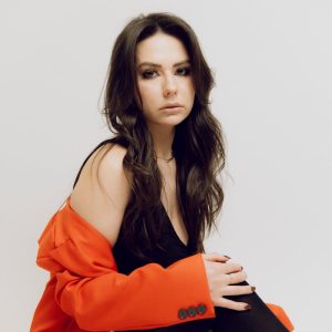 Elegant portrait of a woman in a red jacket on a white background.